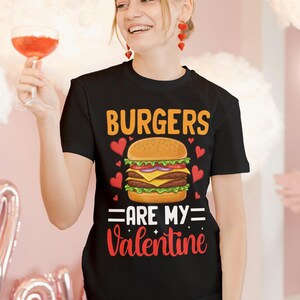 Pu&ograve; includere: Maglietta nera con una grafica di un hamburger e il testo "Burgers are my Valentine".