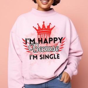 May include: Pink sweatshirt with a graphic print of a crown, wings, and the text "I'm happy because I'm single".