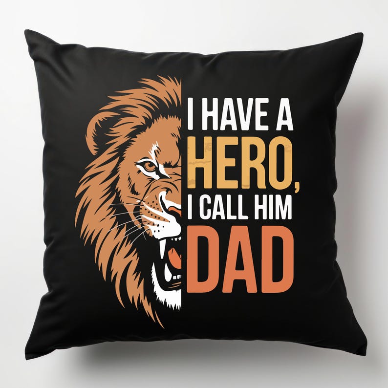 Puede incluir: Almohada negra con la cabeza de un le&oacute;n en el lado izquierdo y el texto "Tengo un h&eacute;roe, lo llamo pap&aacute;" en el lado derecho.