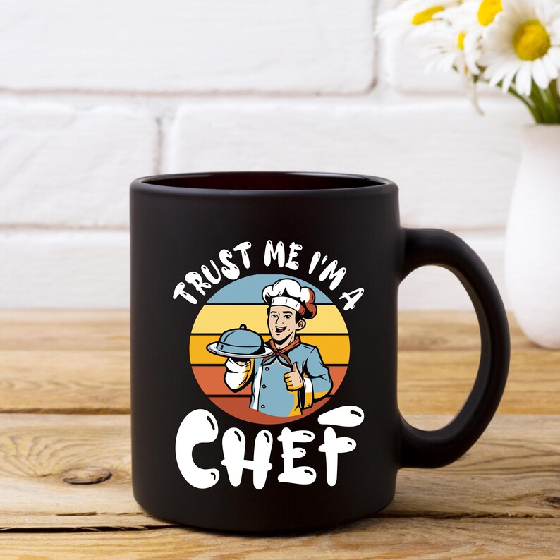 May include: Black ceramic mug with a chef graphic. The graphic features a chef holding a platter with the text "Trust me I'm a Chef" in a circular design above the word "Chef".