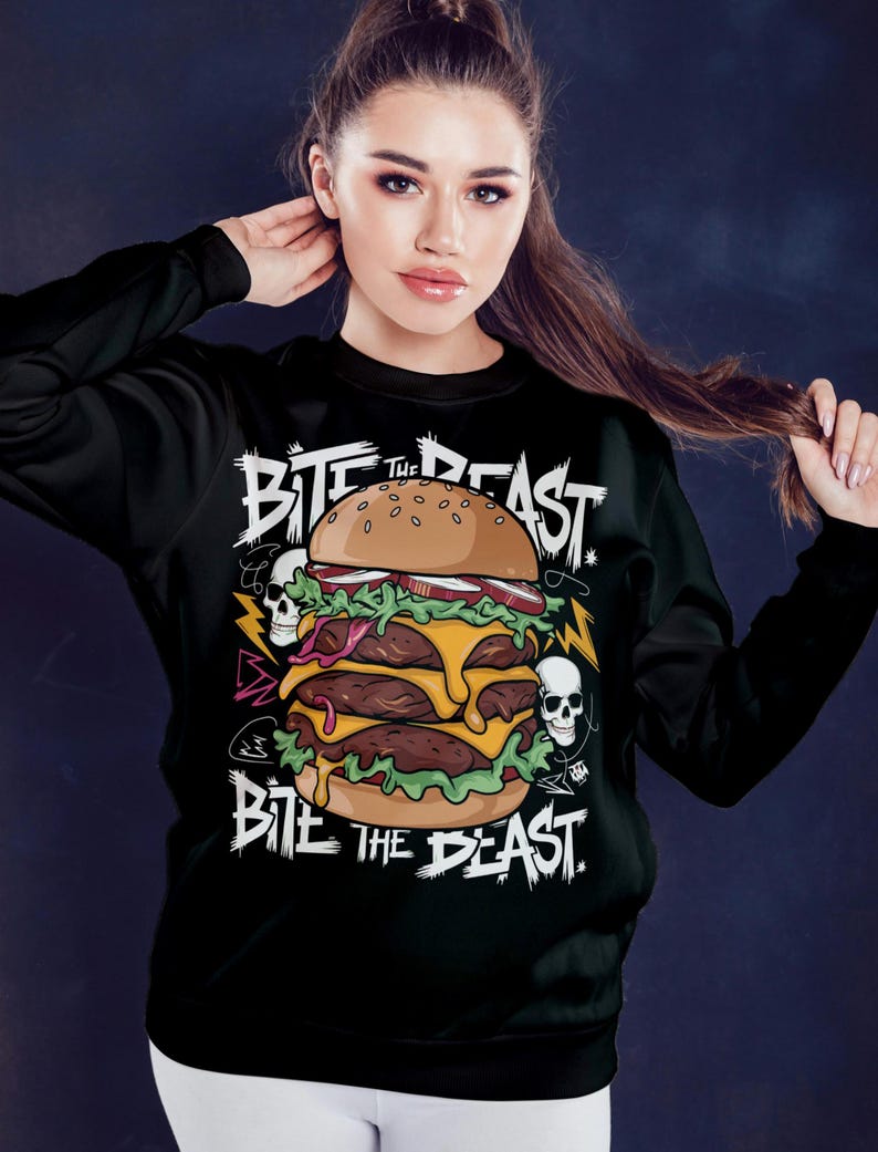 Pu&ograve; includere: Felpa nera con una grafica di un grande hamburger con il testo "Bite the Beast" in lettere bianche e nere.