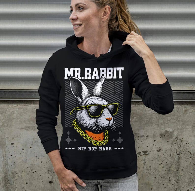May include: A black hooded sweatshirt featuring a graphic print of a rabbit wearing yellow-rimmed sunglasses and a gold chain. The text MR.RABBIT is printed above the rabbit, and the text HIP HOP HARE is printed below the graphic design.