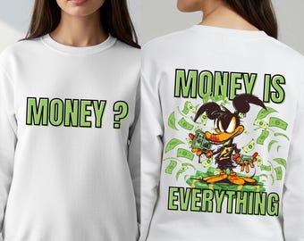 May include: White sweatshirt. The front displays "MONEY?" in green block letters. The back features a cartoon duck character surrounded by money, with "MONEY IS EVERYTHING" in green block letters.