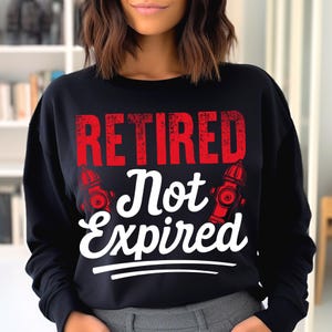 Może przedstawiać: Czarna bluza z napisem "RETIRED Not Expired" w czerwone i białe litery. Projekt zawiera dwa czerwone hydranty. Swobodny top dla emerytowanych strażak&oacute;w.