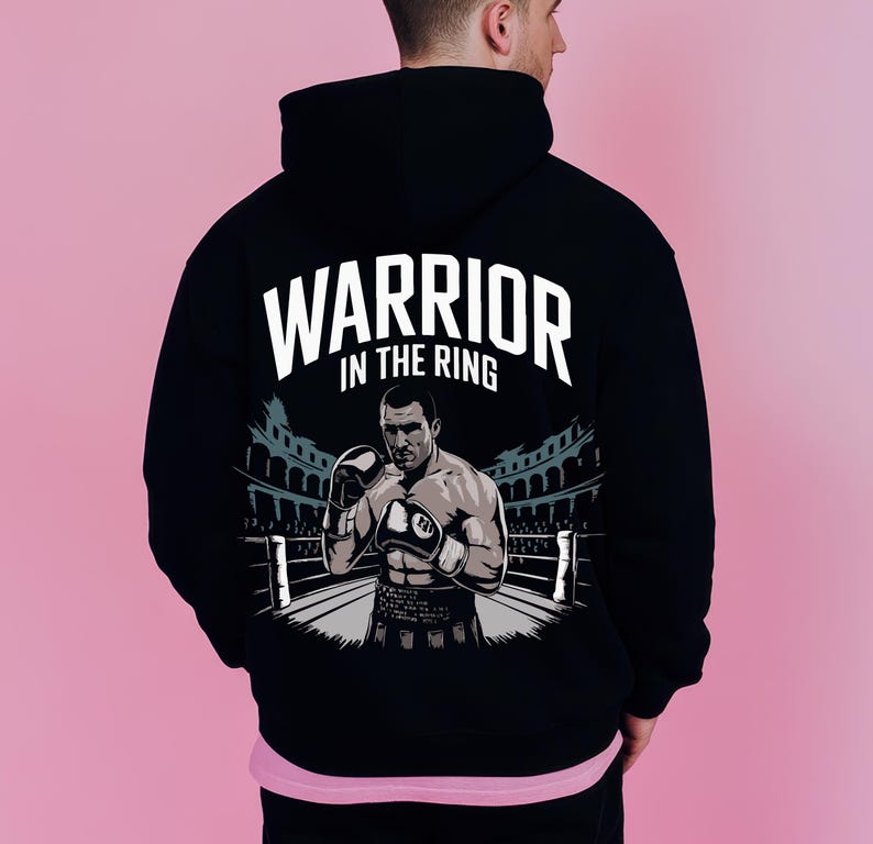 Peut inclure: Sweat-shirt &agrave; capuche noir avec un imprim&eacute; graphique d'un boxeur dans un ring. Le texte "Warrior in the Ring" est imprim&eacute; au-dessus du graphique.