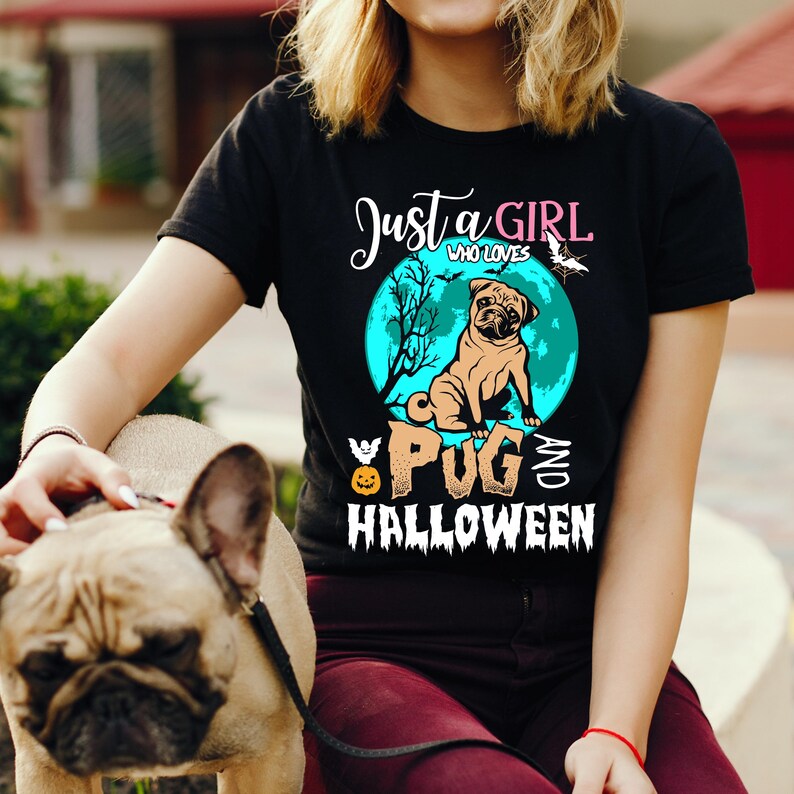 May include: Black t-shirt with a graphic featuring a pug dog, a teal moon, and the words "Just a Girl Who Loves Pugs and Halloween." A French Bulldog is in the foreground.