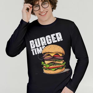 Pu&ograve; includere: Maglietta a maniche lunghe nera con una grafica bianca di un hamburger e il testo "Burger Time".
