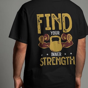 May include: Black t-shirt with a gold graphic that reads "FIND YOUR INNER STRENGTH." The design includes a kettlebell, dumbbells, and stars. The shirt is a classic crew neck.