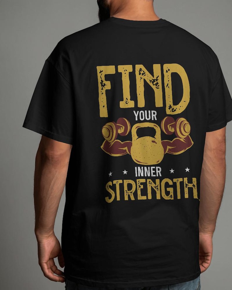 May include: Black t-shirt with a gold graphic that reads "FIND YOUR INNER STRENGTH." The design includes a kettlebell, dumbbells, and stars. The shirt is a classic crew neck.