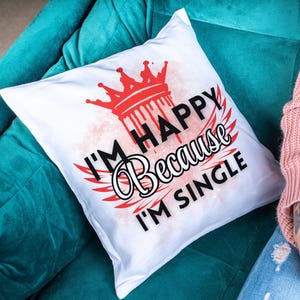 May include: White pillow with a red crown and the text "I'm Happy Because I'm Single" in black.