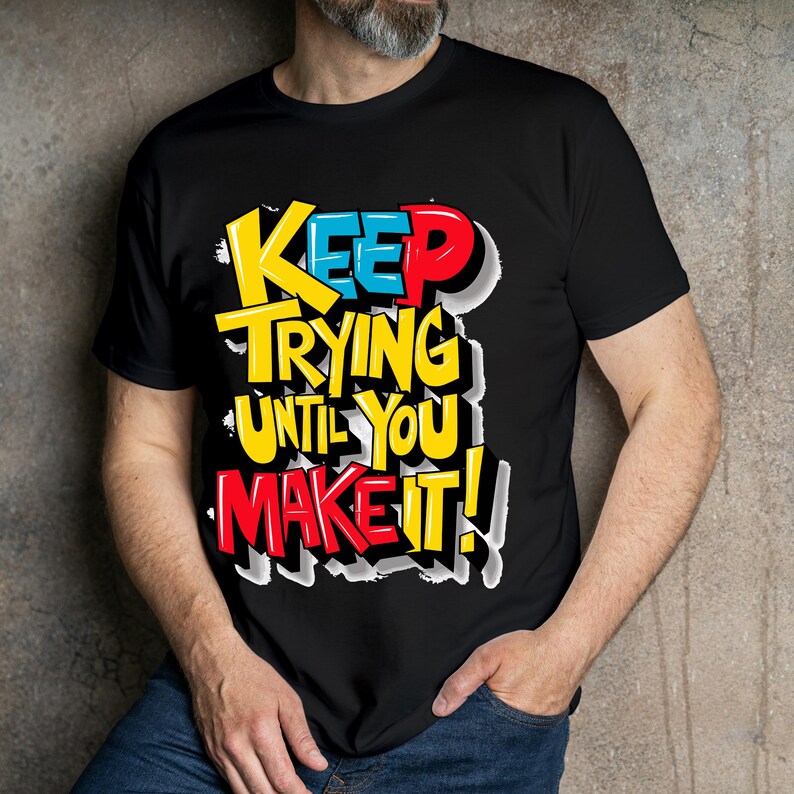 May include: Black t-shirt with a colorful graphic that says "Keep Trying Until You Make It!"
