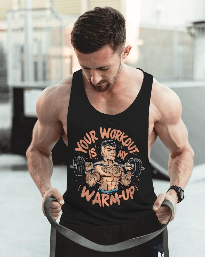 May include: Black tank top with the text "Your Workout Is My Warm-Up" in orange and white. The graphic features a cartoon weightlifter. The tank top is sleeveless and made of a soft material.