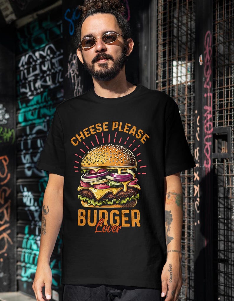 Pu&ograve; includere: Una maglietta nera con una grafica di un cheeseburger e il testo "Cheese Please Burger Lover".