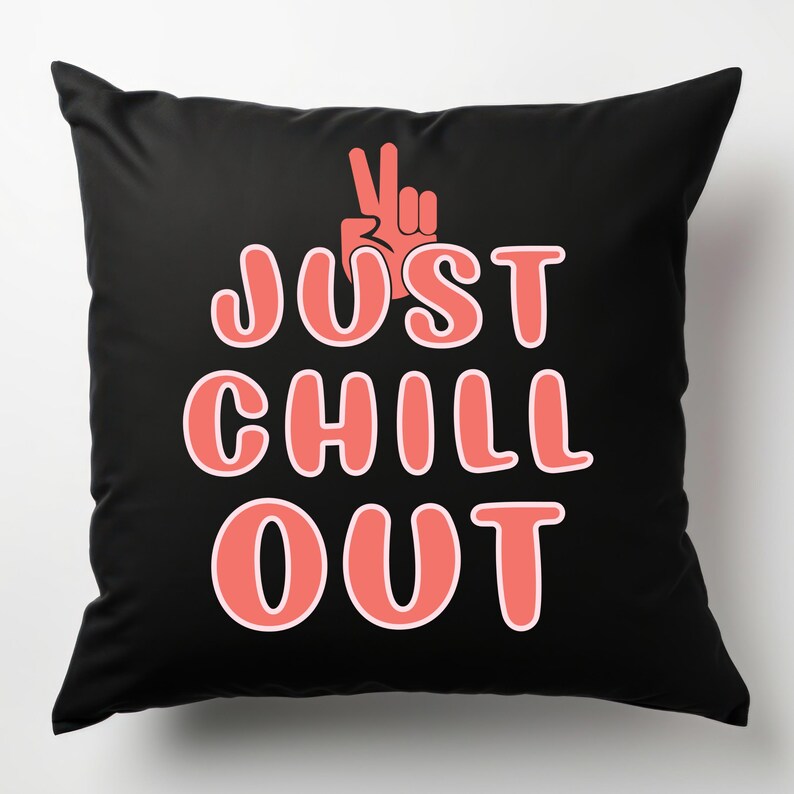 May include: Black square throw pillow with the words "JUST CHILL OUT" in coral-colored letters. A coral-colored hand in a peace sign is above the text. The pillow is a decorative item.