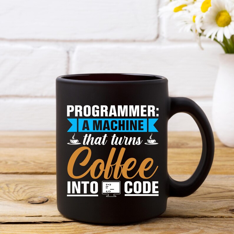 Puede incluir: Taza de caf&eacute; negra con el texto "PROGRAMMER: A MACHINE that turns Coffee INTO CODE" en blanco, azul y naranja. La taza tiene un asa grande y est&aacute; sobre una superficie de madera.