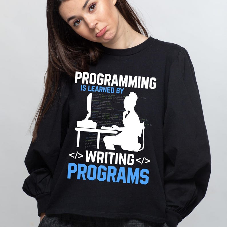 Puede incluir: Camiseta negra de manga larga con el texto "PROGRAMMING IS LEARNED BY WRITING PROGRAMS" en blanco y azul. El gr&aacute;fico muestra una silueta blanca de una persona frente a un ordenador. La camiseta es de cuello redondo.