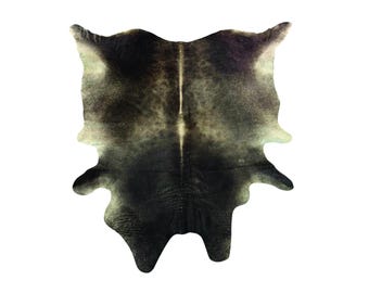 Puede incluir: Una alfombra de piel de vaca con un patrón natural. La alfombra presenta una mezcla de colores negro, gris y beige. La piel tiene una forma y textura únicas, añadiendo un toque rústico a cualquier espacio.