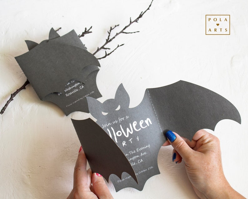 May include: A black bat-shaped invitation card with white text that reads "Join us for a Halloween Party" and includes the date and location. The card is folded in half and the back is blank.