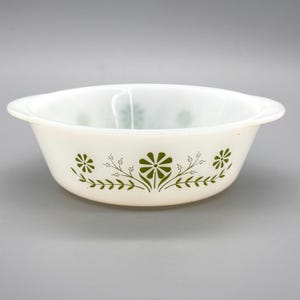 Peut inclure: Bol Pyrex blanc avec un motif floral vert. Le bol a deux poignées et une forme arrondie. Le motif floral comprend des fleurs et des feuilles stylisées. Un article de cuisine vintage.