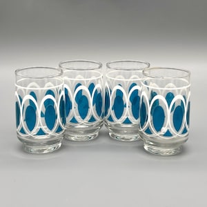 Puede incluir: Cuatro vasos transparentes con un patrón ovalado en color turquesa y blanco. Los vasos son cilíndricos con un borde ligeramente ensanchado. Los óvalos turquesa están dispuestos en un patrón repetitivo, creando una estética retro. Los vasos son adecuados para servir bebidas.