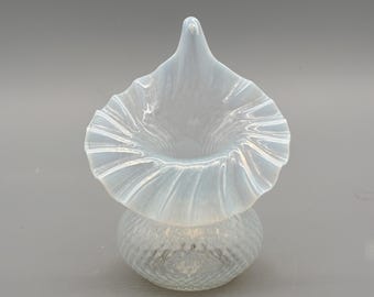 May include: A small, opalescent glass vase with a ruffled rim and a textured, bulbous base. The vase has a flared, trumpet-like opening and a delicate, ethereal appearance. The glass has a subtle, iridescent quality.
