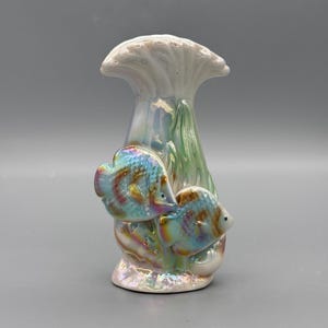 Könnte beinhalten: Eine Keramikvase mit schillerndem Finish, die zwei farbenfrohe Fische und Details von Wasserpflanzen zeigt. Die Vase hat einen ausgestellten oberen Rand und eine strukturierte, perlmuttartige Oberfläche.