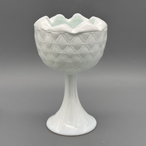 Puede incluir: Una taza de cerámica blanca con un asa negra y el texto "But First, Coffee" en negrita negra. La taza se encuentra sobre un fondo neutro, resaltando su diseño simple.