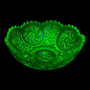 Può includere: Una ciotola di vetro verde brillante con intricati motivi a stella e geometrici. La ciotola ha un bordo smerlato e una forma profonda e arrotondata. Il vetro sembra essere vintage, con una qualità luminosa unica.