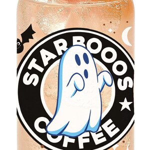 May include: A clear glass can with a black and white Starbucks logo featuring a ghost and the text "Starbooos Coffee". The can is filled with a pink liquid and a slice of orange is on top.