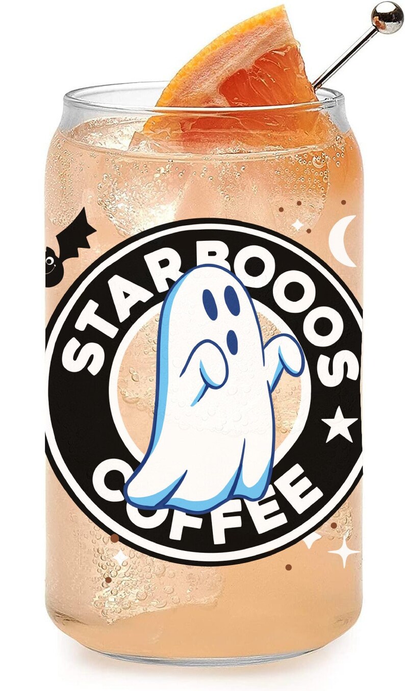 May include: A clear glass can with a black and white Starbucks logo featuring a ghost and the text "Starbooos Coffee". The can is filled with a pink liquid and a slice of orange is on top.