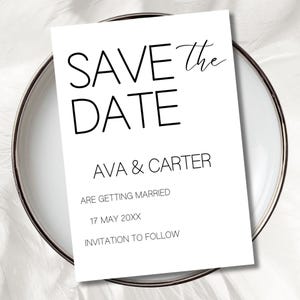 May include: A white 'Save the Date' card with black text, featuring the names 'Ava & Carter' and the date '17 May 20XX'. The card is on a white plate with a silver rim, perfect for wedding announcements.