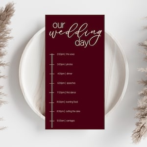 Könnte beinhalten: Eine weinrote Hochzeits-Tagesablaufkarte mit dem Schriftzug "our wedding day" in eleganter Schrift. Der Zeitplan umfasst die Gelübde, Fotos, Abendessen, Reden, Eröffnungstanz, Abendessen, Anschneiden der Torte und Kutschen.