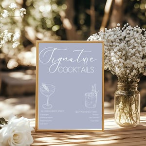 Puede incluir: Un letrero enmarcado con la frase "Signature Cocktails" en escritura cursiva. El letrero presenta ilustraciones de dos cócteles con sus ingredientes. El fondo es de color lavanda claro.