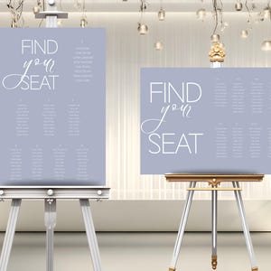 Puede incluir: Dos planos de asientos de boda azul claro con texto blanco sobre caballetes. El texto en los gráficos dice "FIND your SEAT" en una fuente de escritura. Los gráficos también enumeran nombres y números de mesa. Los caballetes son plateados y dorados.
