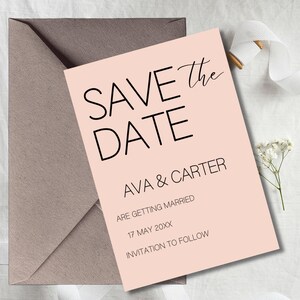 Puede incluir: Una tarjeta rosa pálido de 'Save the Date' con texto negro, con los nombres 'Ava & Carter' y detalles de la boda. La tarjeta se presenta con un sobre gris y una ramita de flores blancas.