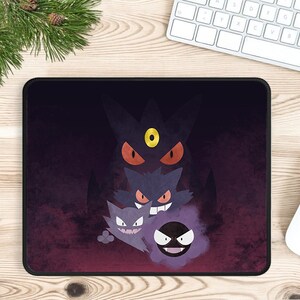 May include: Black mousepad featuring a group of cartoon ghost characters with red eyes and purple and black coloring. The mousepad has a black border and is on a wooden surface.