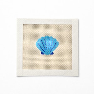 May include: Square needlepoint canvas featuring a blue seashell design. The seashell is centered on a beige background, framed by a white border. The design is a simple, yet elegant, nautical theme.