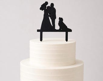 Cake topper of a bride and groom with a child and a dog