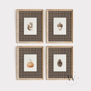 May include: Set of four framed art prints featuring watercolor illustrations of autumn elements. Includes a squirrel, acorn, pumpkin, and pinecone. Each print is set against a plaid background and framed in a light wood.