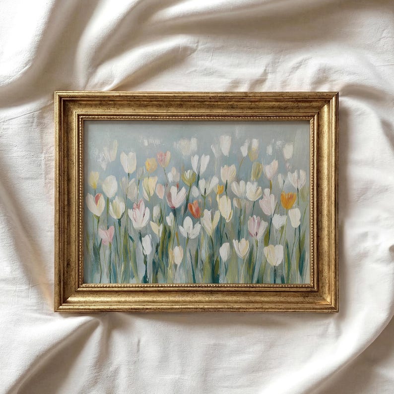 Puede incluir: Una pintura rectangular en un marco dorado que muestra un campo de tulipanes blancos, rosa p&aacute;lido y naranja suave con tallos verdes sobre un fondo azul claro. La obra de arte presenta pinceladas visibles y una est&eacute;tica suave.