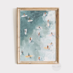 May include: Framed art print depicting a serene ocean scene with numerous surfers on their boards. The artwork features a palette of blues and whites, with a golden-toned frame. The surfers are small figures, adding a sense of scale to the artwork.