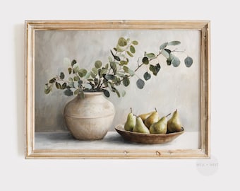 May include: A framed still life painting featuring a beige ceramic vase with green leafy branches, a wooden bowl filled with green pears, and a neutral background. The frame is a light, distressed wood.