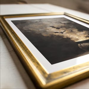May include: A framed print depicting a dramatic scene with bats silhouetted against a cloudy, sepia-toned sky. The artwork is encased in a gold-coloured frame. The print's dark tones and imagery create a mysterious atmosphere, perfect for Halloween or gothic decor.