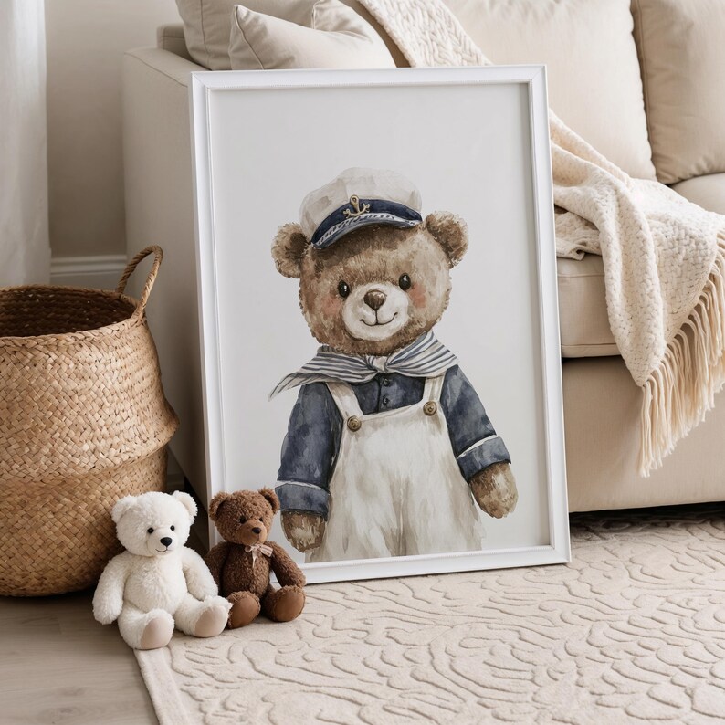 May include: A framed wall art print featuring a watercolor illustration of a brown teddy bear dressed as a sailor. The bear wears a white captain's hat with a blue anchor emblem, a blue and white striped neckerchief, and white overalls.