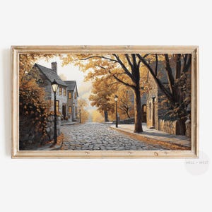 May include: A painting depicting a cobbled street lined with houses and trees in autumn. The street is made of cobblestones and the houses are painted in shades of grey. The trees are a mix of yellow, orange, and red. There are streetlights on either side of the street.
