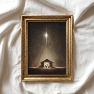 May include: A framed wall art piece featuring a dark, sepia-toned painting of a nativity scene inside a small stable. A bright, glowing star shines directly above the structure, casting a soft light downward onto the figures within the stable.