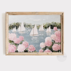 May include: A framed painting depicts sailboats on a lake, surrounded by pink and white flowers. The artwork has a light blue sky and green trees in the background. The frame is a light brown color.