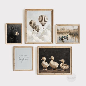 May include: A set of framed art prints with vintage illustrations. The collection includes a black bear portrait, hot air balloons, ducks on a pond, ducklings, and a print with the text "Long Live boyhood". The frames have a wooden finish.
