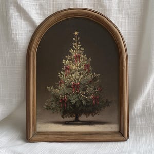 May include: A framed Christmas tree painting. The tree is decorated with red bows and string lights, topped with a gold star. The frame is a light brown wood with an arched top. The background is a dark brown.