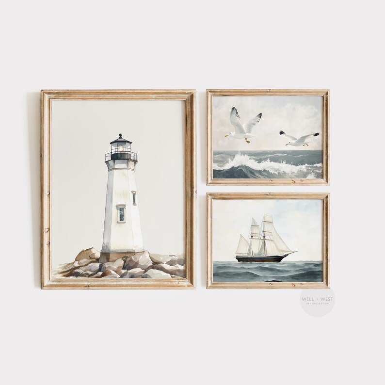 May include: Set of three framed watercolor prints featuring nautical themes. Includes a lighthouse on rocks, seagulls over ocean waves, and a sailboat on the water. The frames are light brown.
